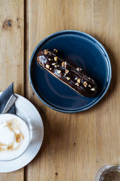 Chocolate eclair on plate with glass of coffee