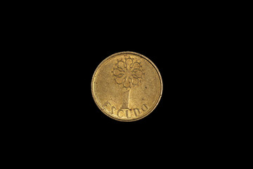 An old, gold one escudo coin from Portugal, shot close up in macro on a solid black background