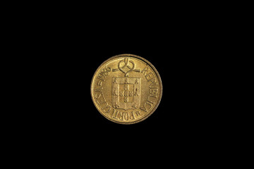 An old, gold one escudo coin from Portugal, shot close up in macro on a solid black background