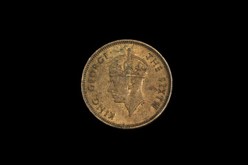 A close up, shot in macro image of an old ten cent coin from British Hong Kong, shot against a solid black background