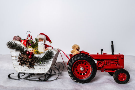 Santa in sleigh being pulled by teddy bear on red tractor