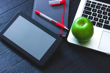 WORK TABLE WITH LAPTOP, TABLET, NOTEBOOK, BOLYGRAPH AND GREEN APPLE