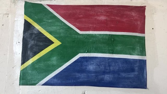 hand held close shot of a hand painted national flag of the Republic of South Africa on a white wall on a sunny summer day. urban graffiti street aert design as filler for travel and national pride