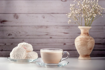 Cup of hot latte coffee with marshmallows on a white table