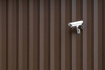 Building with Surveillance or Security Camera on metal brown wall, corrugated texture, galvanized steel surface, Abstract architectural pattern for background with copy space