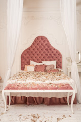 Chic retro king size bed strewn with feathers from the pillow. Pillow fight in the room