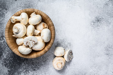 Raw white mushrooms in a bamboo bowl. Gray background. Top view. Space for text