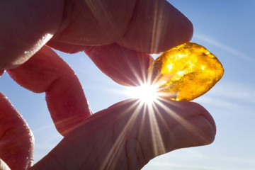 male hand holds amber against the sun
