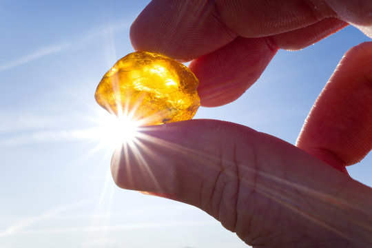 male hand holds amber against the sun