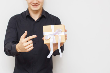 Man with a happy face and a gift box, pointing at that. With Copy-space.