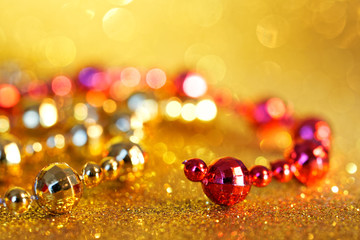 Red and golden Christmas tinsel on a yellow sparkling background. Defocus show. Blank for greeting...
