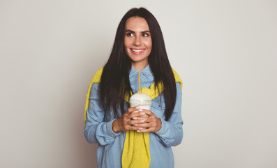 My pumpkin latte. Close-up photo of a magnificent young lady with long jet-black hair, who is looking to the left and holding her coffee to go in her hands.