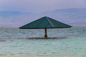 Low Point Of View on Dead Sea water. Sunshade in the water, a testament to the rising water level.