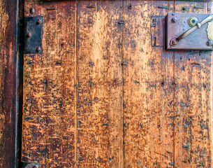 Closeup fragment of a beautiful antique door with a rusty padlock and hinges. Old textured antique doors. Vintage background.