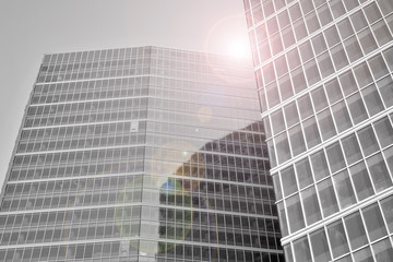 Modern office building wall made of steel and glass with blue sky. Glass surface with sunlight. Black and white.