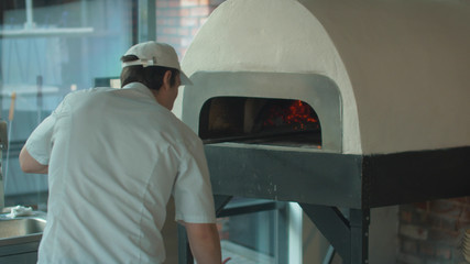 Cook in uniform mixes wooden logs in the oven
