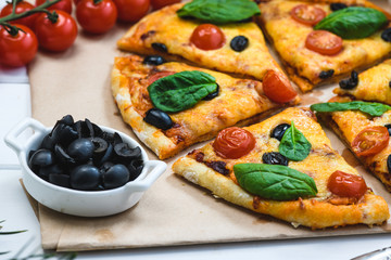 Pizza with tomatoes and spinach on a white background and Christmas fir branches