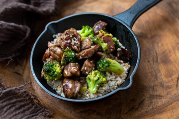 Beef and broccoli over rice in a black skillet topped with sesame seeds 