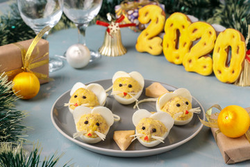 Festive snack Mice for 2020 made of stuffed eggs with cod liver on a light blue background, Symbolic food for the new year, horizontal orientation
