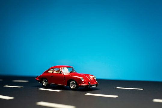 Side View Of A Porsche Carrera 2 Toy Model Car On A Blue Background.