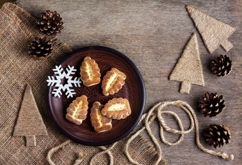 Rustic winter composition with shortbread cookies on a plate and pinecones