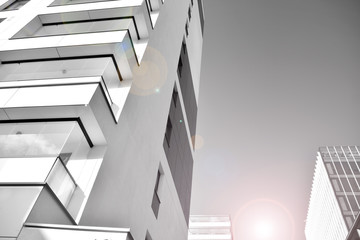 Obraz premium Detail of modern residential flat apartment building exterior. Fragment of new luxury house and home complex. Glass surface with sunlight. Black and white.