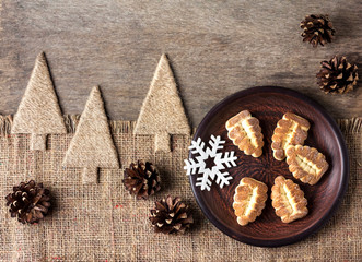 Rustic winter composition with shortbread cookies on a plate and pinecones