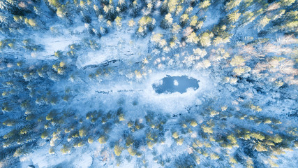 Aerial view of the snowy forested hills and frozen small lake in Nuuksio nature park in Finland.