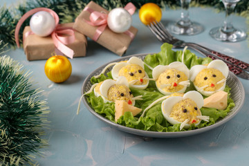 Festive snack Mice for 2020 made of stuffed eggs with cod liver on a light blue background, Symbolic food for the new year, horizontal orientation