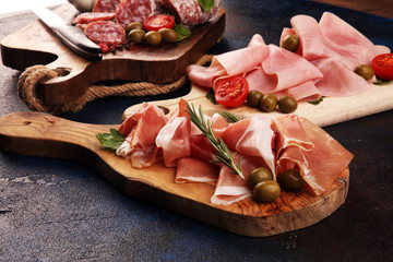 Food tray with delicious salami, pieces of sliced prosciutto crudo, sausage and basil. Meat platter