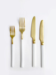 White golden cutlery view from above on a white background. Top view..Knife and fork for a festive table for a wedding, birthday or party.