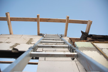 Stepladder on the wall to the roof. A stepladder at a construction site. Bottom up view