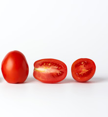 ripe red whole tomatoes and pieces on a white background, autumn harvest