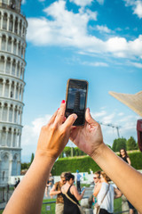 Tourist girl in Pisa, Italy. Woman photographing with mobile cell phone the historical monument