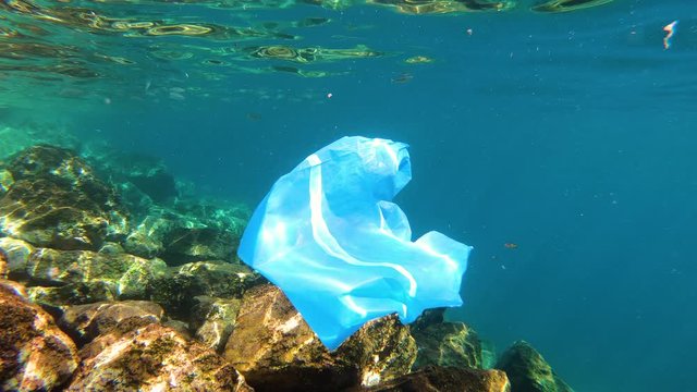 Discarded Blue Plastic Bag Drifts Underwater in the Ocean. Plastic pollution in water.  Plastic waste in the sea
