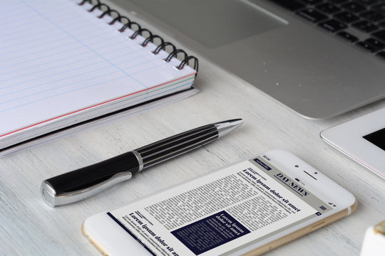 Office desk table with computer, tablet, supplies and Breaking News on smartphone