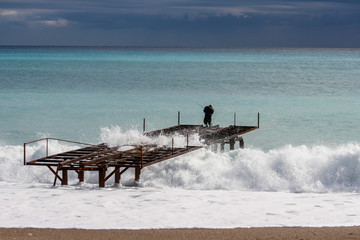 Fototapeta na wymiar an Iron Pier and fisherman among the waves