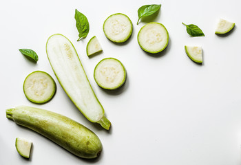 Creative layout of solid and sliced zucchini on white background with space for text. Isolated vegetables on white background. View from above