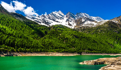 Fototapeta na wymiar Green lake in Gran Paradiso Italian alps mountains in Graian Alps in Piedmont, Italy with snow capped peaks.