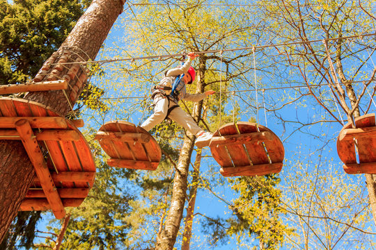 Portrait of cute little boy and girl walk on a rope bridge in an adventure rope park.