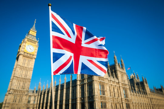 Single Union Jack flag waving in front of Big Ben at the Houses of Parliament in London, UK on a clear sunny day