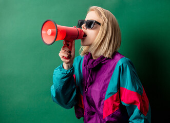 woman in 90s style punk jacket with loudspeaker on green background