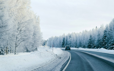 Fototapeta na wymiar Car on Winter road with snow in Finland. Auto and Cold landscape of Lapland. Automobile on Europe forest. Finnish City highway ride. Roadway and route snowy street trip. Driving