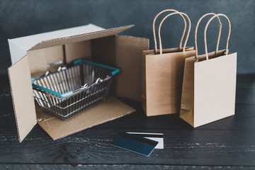 online shopping, parcel with shopping basket and bags next to it with gift cards or payment cards