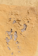 Close-up of a weathered and old concrete wall, yellow paint is peeling off. High resolution abstract full frame textured background.