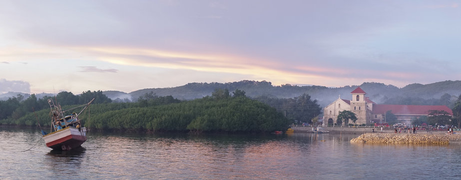Sunset over the ocean with orange sky at the Baclayon Church on Bohol Island near Cebu City, Philippines.