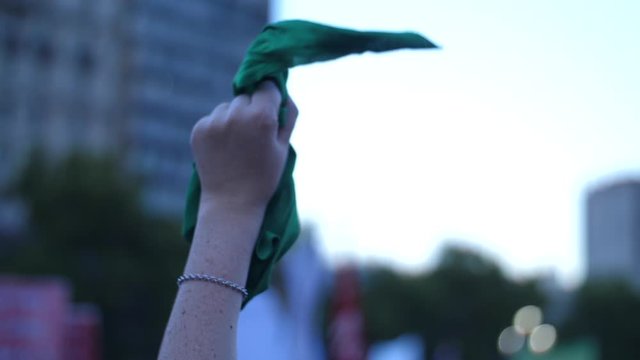 Hand waving green handkerchief while marching in favour of abortion law