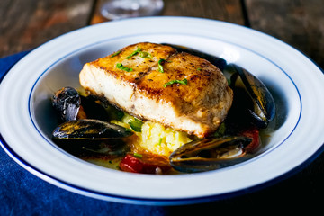 Fried fish fillet with mussels in plate on the table.