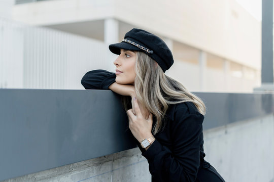 Young blond businesswoman wearing black sailor's cap and looking sideways