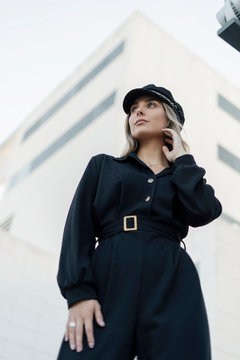 Young blond businesswoman wearing black sailor's cap and looking sideways, low angle view